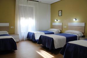 托莱多马德里旅馆的一间设有三张床的客房,配有蓝色和白色的床单