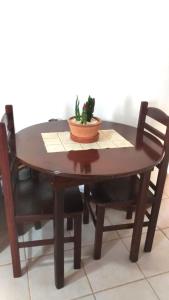 阿蒂巴亚Pousada Montanha da Pedra Grande的一张木桌,上面有两把椅子和一株植物