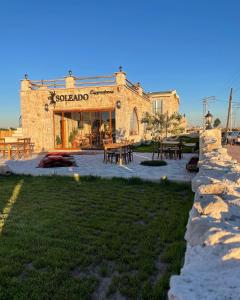 乌奇希萨尔Soleado Cappadocia Hotel的一座石头建筑,前面设有桌子和桌子