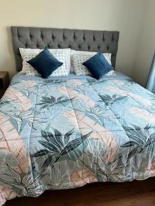 塔尔卡Casa Sector Oriente Talca的一张带蓝色枕头的色彩缤纷的被子的床