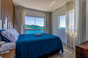 阿拉亚尔-杜卡布Villa Orion的一间卧室设有蓝色的床和大窗户