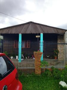 佩洛塔斯Kitnet SIMIROMBA的前面有栅栏和一辆红色汽车的房子