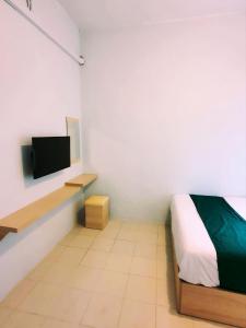 名古屋Homestay 81 Batu Batam的一间卧室配有一张床,墙上配有电视