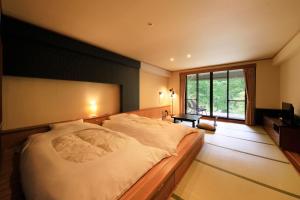 日光四季彩酒店(Hotel Shikisai)的一间卧室设有一张大床和一个大窗户