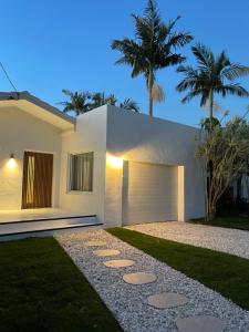 巴利纳Entre Palmas Ballina的一座白色的房子,设有车库和棕榈树