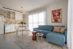 特拉维夫YalaRent Flora- Designed 1BR penthouse in Florentin的一间带蓝色沙发的客厅和一间厨房