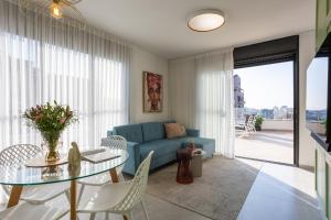 特拉维夫YalaRent Flora- Designed 1BR penthouse in Florentin的客厅配有蓝色的沙发和玻璃桌