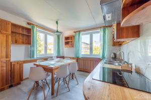 科沃布热格Horyzont Apartamenty -Domek na Sosnowej z tarasem的厨房配有木桌、椅子和窗户。