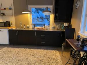 灵塞德House with garage in central Lyngen的厨房配有黑色橱柜、桌子和窗户。
