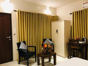 尼甘布Ceylon Kingsmen Garden Hotel - Katunayake的一间房间,配有两把椅子和一张鲜花桌子