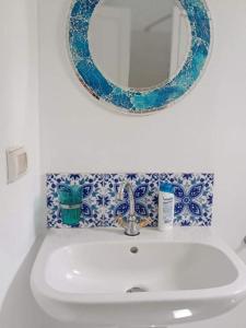 乌姆苏克Dar Janis Djerba دار يانيس جربة的浴室水槽设有镜子,铺有蓝色和白色的瓷砖