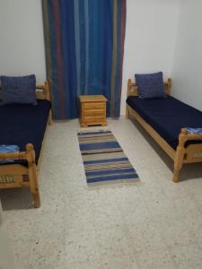 乌姆苏克Dar Janis Djerba دار يانيس جربة的客房设有两张床、床头柜和桌子。