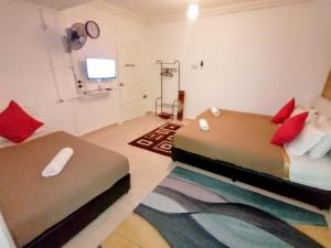 马兰Fishing Village Marang Terengganu的一间卧室配有两张带红色枕头的床和电视。