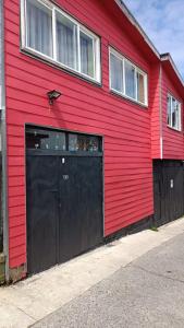 蒙特港"Mi Hostal Tu Casa" Hostal Familiar SOLO EMPRESAS, TURISTAS y VIAJEROS的一座红色的建筑,设有大型黑色车库