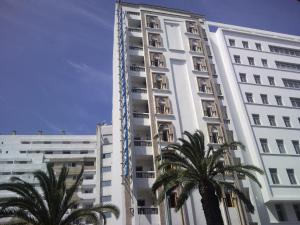 卡萨布兰卡摩洛哥家园酒店 的一座高大的白色建筑,前面有棕榈树