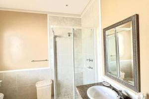 DʼAlmeidaLuxury at Pinnacle Point - 3 Bedroom Villa的带淋浴、盥洗盆和镜子的浴室