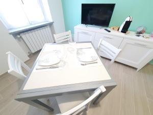 卡萨莱蒙费拉托Appartamento Il Castello的白色的餐桌、椅子和电视