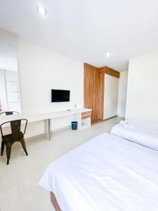 巴厘巴板Pillow Guest House的白色卧室设有1张床和1张带电视的书桌