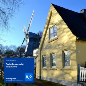 弗伦斯堡Ferienhaus an der Bergmühle的风车前有标志的房子