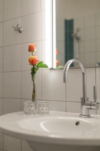 埃门丁根马克格拉夫商务艺术旅馆的浴室水槽,花瓶里放着花