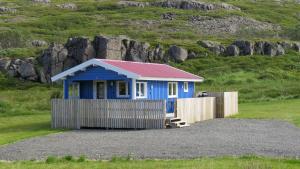 DrangsnesHvammur 4 with private hot tub (Fagurgali)的山坡上一座蓝色的房子,屋顶为红色