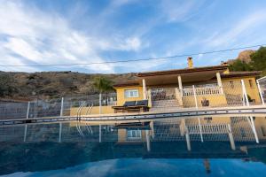 CobatillasCasa Rural Familiar Piscina Sierra Balumba的一座黄色的房子,前面有一个游泳池