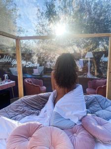 卡塔尼亚Bubble Glamping Sicily的躺在床上看窗外的女人