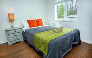 哈里伯顿Mountain House in the Heart of Haliburton, Mins to Lake的一间卧室配有带橙色枕头的床和窗户。