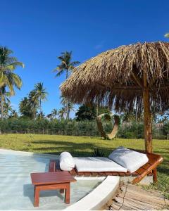 托弗海滩Casa Bali Tofo的一张带草伞和桌子的床