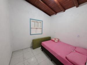 拉古纳Casa temporada praia da galheta 3的卧室配有粉红色的床和窗户。