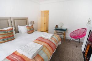 考斯Paskins, Cowes - Sleeps 4 - 2 Bed - 2 Bath - Central Location的一间卧室配有两张床和一张粉红色的椅子