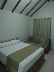库尼亚Pousada Vale do Parque的一间卧室配有一张大床和一张沙发