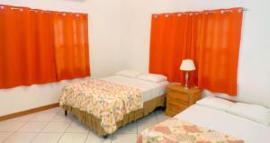 克朗角Ursula Guesthouse in Bon Accord的一间卧室配有两张床和橙色窗帘