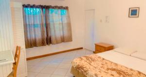 克朗角Ursula Guesthouse in Bon Accord的一间卧室配有一张床、一张书桌和一个窗户。