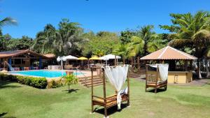 塞古罗港Pousada Beach Bahia的一个带游泳池、两把椅子和遮阳伞的度假村