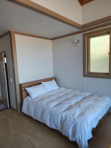 江陵市Gyeongpodae Darakbang的卧室配有一张大白色床和窗户