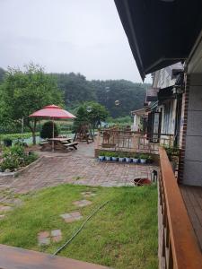 江陵市Gyeongpodae Darakbang的庭院设有野餐桌和遮阳伞。