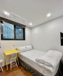 首尔318 Stay - Foreigners Only的一间卧室配有一张床、一张桌子和一个窗户。
