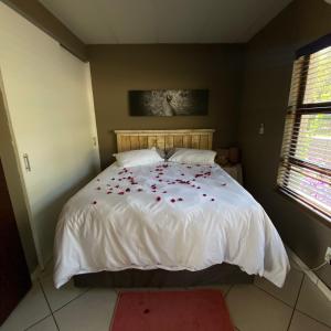 约翰内斯堡Glenvista Home with a View的卧室配有白色的床铺,上面有红色的鲜花