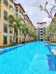 迪沙鲁Balini Home Tiara Desaru的一座棕榈树的大型游泳池位于酒店大楼前