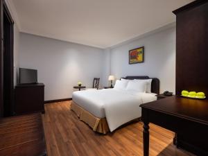 河内Minasi Premium Hotel的酒店客房配有一张床、一张书桌和一张四柱床