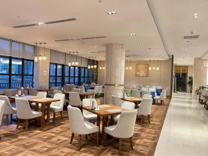 广州广州南鸿澳斯特酒店的配有木桌和白色椅子的餐厅