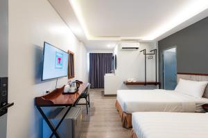 清迈Luck Thai Hotel的酒店客房设有两张床、一张桌子和一台电视。
