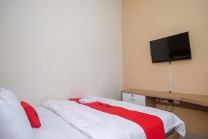 梭罗RedDoorz Plus near UMS Solo 2的卧室配有一张床铺,墙上配有电视