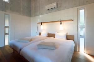 读谷村オーシャンビュー非日常を味わえる空間プライベートバーベキューm yomitan nagahama的卧室配有一张带两个枕头的大白色床
