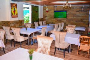 KaratinaOmega Gardens Hotel的一间带桌椅和电视的餐厅