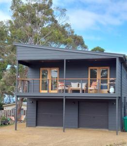 Surveyors BayThe Beach Box at Big Roaring Beach Tasmania的带阳台和桌椅的灰色房屋