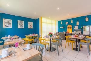 布雷斯地区布尔格Appart'City Classic Bourg-en-Bresse的餐厅拥有蓝色的墙壁和桌子以及黄色的椅子