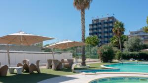 阿尔巴·阿德里亚蒂卡Hotel Sporting的一座带椅子和遮阳伞的游泳池位于一座建筑旁边