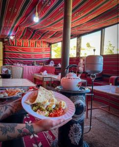 Al Jāyah7 Caves Hotel的餐馆里拿着一盘食物的人